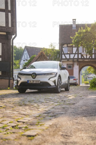 A white car on a cobbled street in a village with half-timbered houses and a summery atmosphere, Renault Megane, Deer E- Carsharing, electric car, Gechingen, Germany