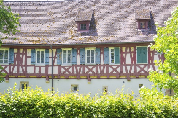 Historic half-timbered house with small windows behind green hedges, event and wedding location Lorch Monastery, Lorch, Germany