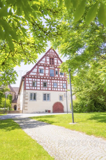 Half-timbered house with cobblestone path and surrounded by green trees under a clear sky, event and wedding location Lorch Monastery, Lorch, Germany