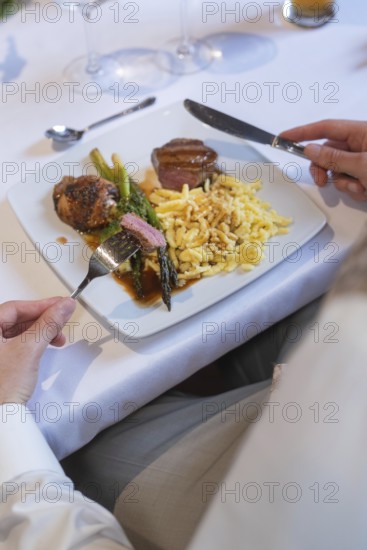 A plate of meat, asparagus and spaetzle on a white table with cutlery, event and wedding location Kloster Lorch, Lorch, Germany