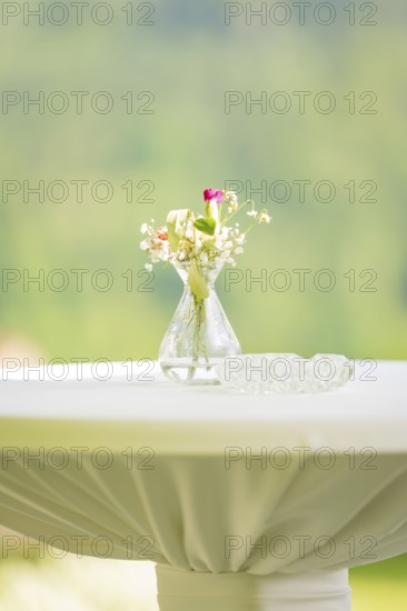 White table with a small flower vase and an ashtray in front of a blurred background, event and wedding location Kloster Lorch, Lorch, Germany