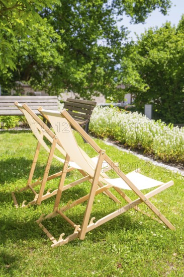 Two wooden deckchairs on a green lawn in the sunny summer garden under trees, event and wedding location Lorch Monastery, Lorch, Germany