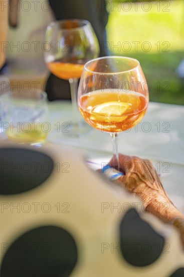 Person holding glass with orange coloured drink at a garden party in summer atmosphere, event and wedding location Kloster Lorch, Lorch, Germany