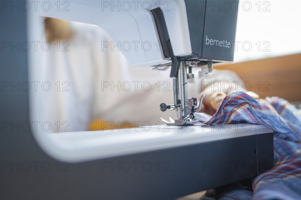 Details of the sewing process with needle and fabric in a well-lit environment, focus on the machine