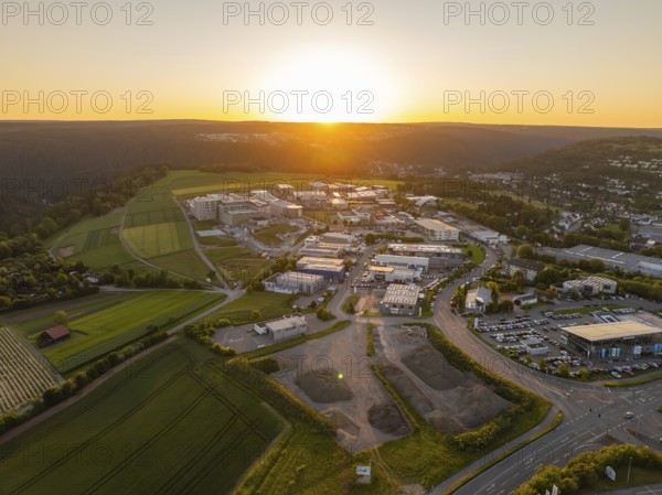Industrial area at sunset, surrounded by fields and rolling hills, Calw, Black Forest, Germany