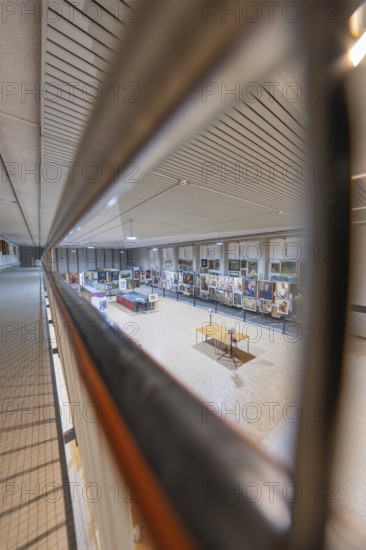 Through a railing you look at an exhibited collection of artworks under a modern structured ceiling, historical art exhibition in the old swimming pool, Schaudepot, Calw, Black Forest, Germany