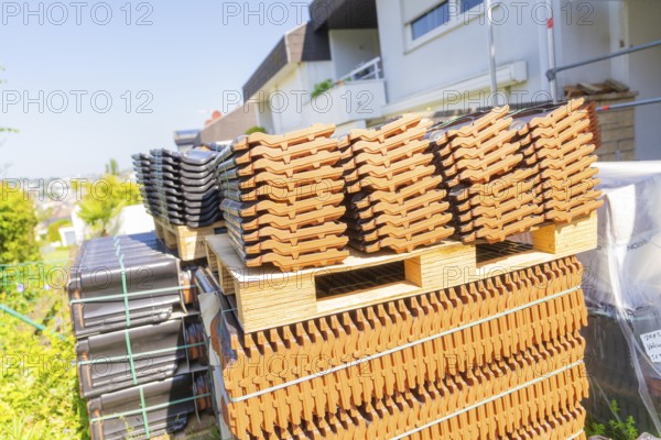 Stacked roof tiles on pallets outdoors in sunny weather, roof renovation, house construction, Pforzheim, Germany