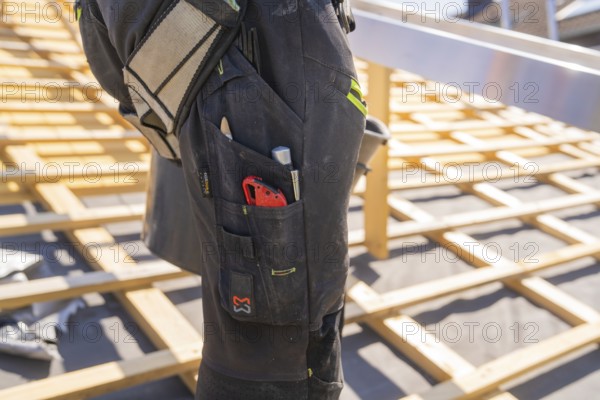 Construction worker on roof construction with tools in his trouser pocket, roof renovation, house construction, Pforzheim, Germany