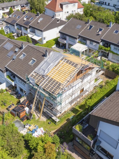 A house with scaffolding and partially new roof, surrounded by a green residential area, roof renovation, house construction, Pforzheim, Germany