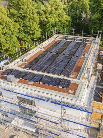 View of a construction site with solar panels on the roof, surrounded by green trees, Hirsau, Calw, Germany