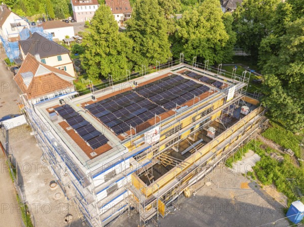 Building under construction with solar cells on the roof, surrounded by houses and trees, Hirsau, Calw, Germany