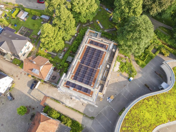 Aerial view of a construction site with solar modules on the roof, surrounded by gardens and houses, Hirsau, Calw, Germany