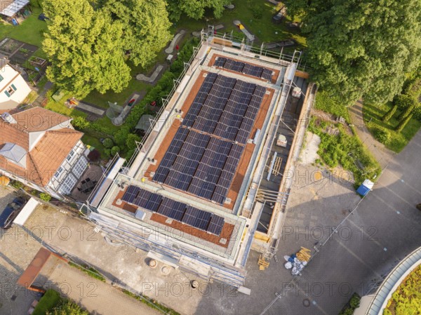 Roof of a construction site with solar cells, surrounded by trees and other buildings, modern construction project, Hirsau, Calw, Germany