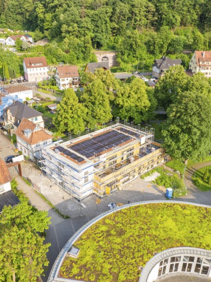 Aerial view of a construction site in a residential area surrounded by trees and green roofs on a summer's day, Hirsau, Calw, Germany