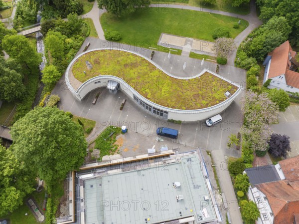 Architecturally curved building with green roof and vehicles in the car park, Hirsau, Calw, Germany
