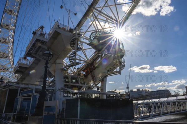 Sunlight streaming through the passenger cabin of the london eye ferris wheel, illuminating the iconic structure against a clear blue sky