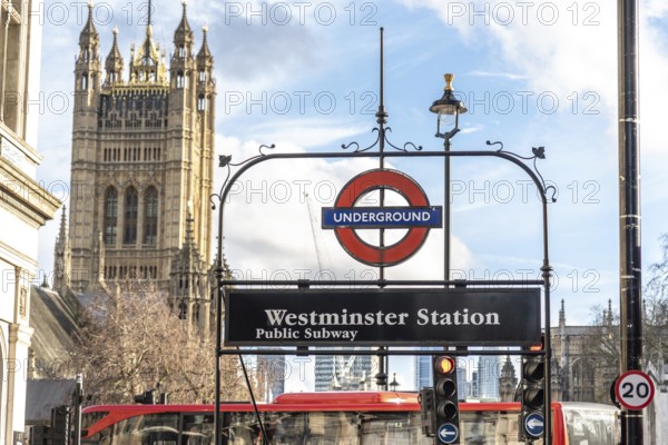 Westminster underground station sign with the houses of parliament, including the victoria tower, in the background in london, uk