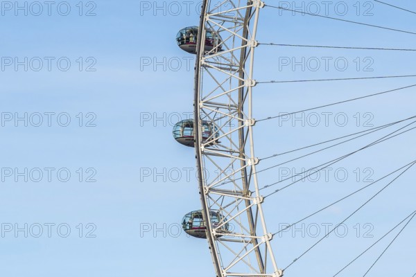 Glass capsules slowly rotating on the london eye ferris wheel against a clear blue sky, offering breathtaking panoramic views of the city