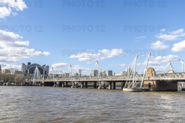 Modern pedestrian golden jubilee bridges flanking the railway hungerford bridge over the river thames with charing cross station in the background, london, uk