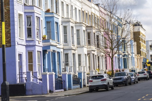 Pastel colored houses create a picturesque scene along a london street, showcasing the city's unique charm