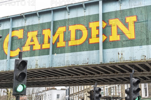 Camden town sign painted on a railway bridge in london, featuring a green light and urban buildings in the background