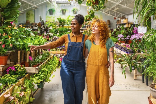 Two young women walking through a garden center, discussing plants and sharing knowledge while enjoying their work in a vibrant greenhouse
