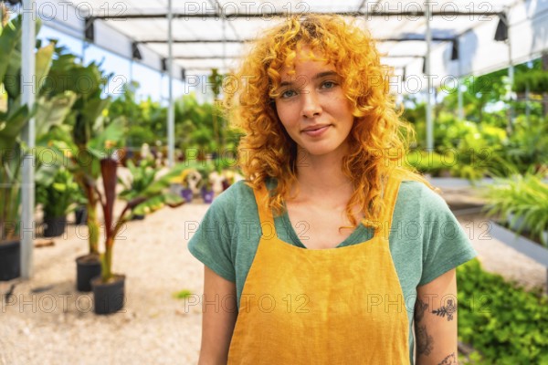 Confident young female gardener working in a vibrant greenhouse, surrounded by thriving plants and enjoying her passion for horticulture