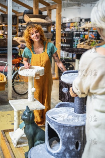 Saleswoman engaging with a customer while presenting various cat scratching posts inside a pet shop, highlighting options and providing assistance