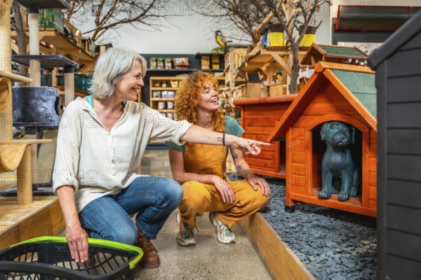 Pet shop worker assisting a customer with a shopping basket, pointing out various dog kennels and discussing options for pets