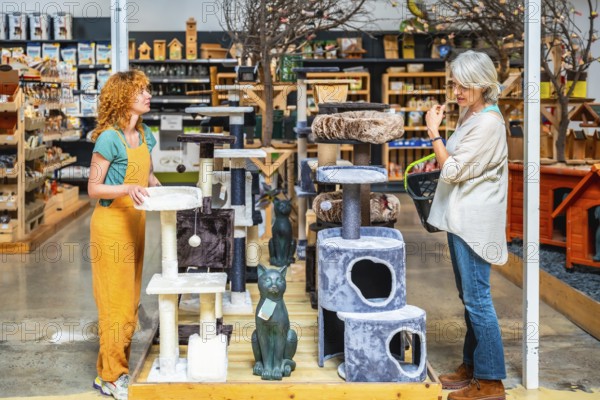 Pet shop assistant displaying various cat trees while helping a customer select the perfect accessories for her beloved feline companion