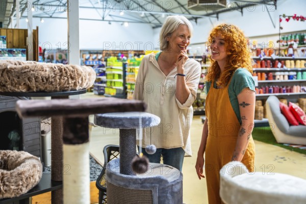 Happy senior woman selecting a cat tree while receiving assistance from a friendly shop assistant in a bustling pet store