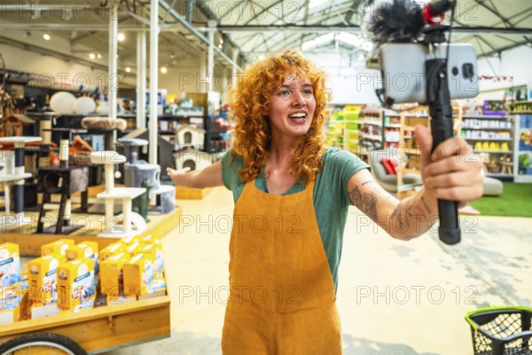 Young saleswoman filming a video for social media with a smartphone and microphone, showing pet products in a pet shop
