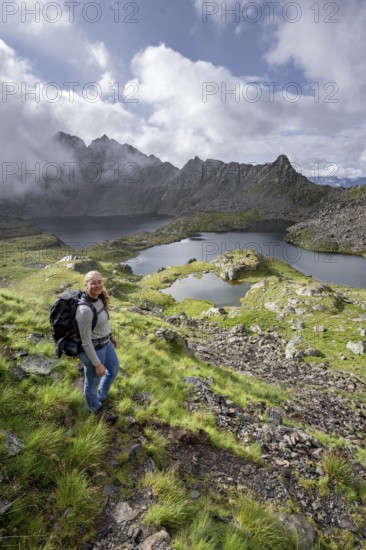 Mountaineer on hiking trail, view of mountain landscape with mountain lakes Wangenitzsee and Kreuzsee, cloudy mountain peaks in the morning light, Schober Group, Hohe Tauern National Park, Carinthia, Austria