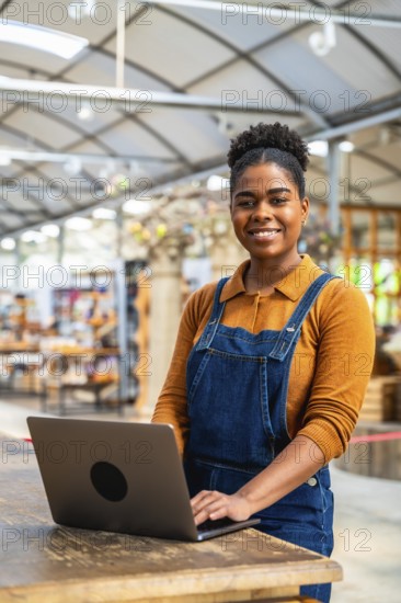 Confident young woman managing greenhouse inventory using a laptop, showcasing modern agriculture practices