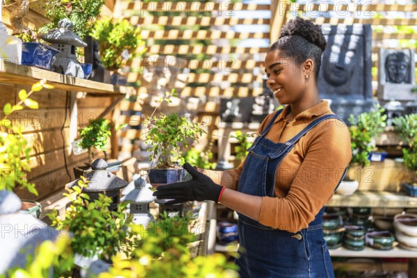 Smiling young woman working in a vibrant plant shop, holding a small bonsai tree and showcasing her passion for gardening and nature