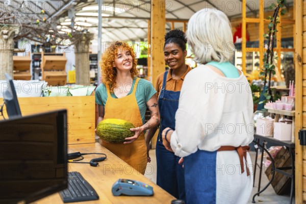 Two young shop assistants engaging with a customer while showcasing a fresh melon in a vibrant grocery store setting