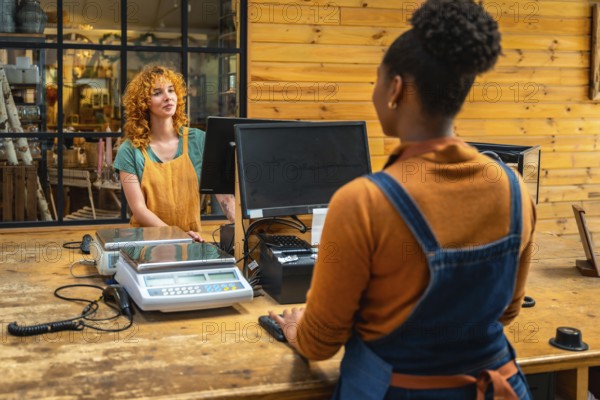 Female shop assistant serving customer at checkout counter in flower shop, using computer and scales