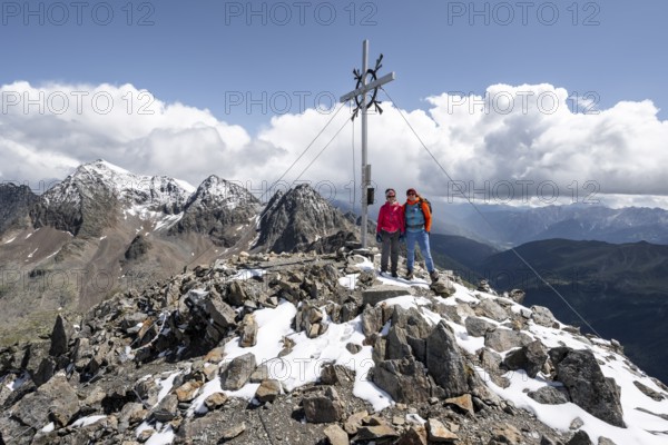 Two female mountaineers on the summit of the Keeskopf with summit cross, behind them summit of the Petzeck, Hoher Perschitzkopf and Kruckelkopf, Schober group, Hohe Tauern National Park, Carinthia, Austria