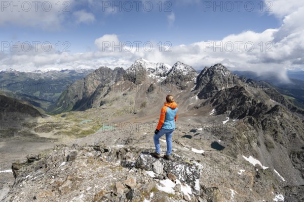 Mountaineer in rocky mountain landscape, at the summit of Keeskopf, behind summit of Petzeck, Hoher Perschitzkopf and Kruckelkopf, Schober Group, Hohe Tauern National Park, Carinthia, Austria