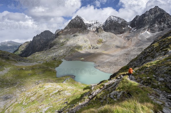 Mountaineer on hiking trail, view of turquoise-blue mountain lake Großer Gradensee, behind summit of Petzeck and Kruckelkopf, Schober group, Hohe Tauern National Park, Carinthia, Austria
