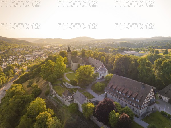An idyllic village with a church, half-timbered houses and lush forest in warm sunlight, event and wedding location Kloster Lorch, Lorch, Germany