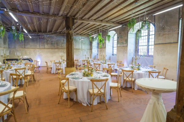 Rustic wedding setting with round tables and natural lighting through windows, event and wedding location Lorch Monastery, Lorch, Germany