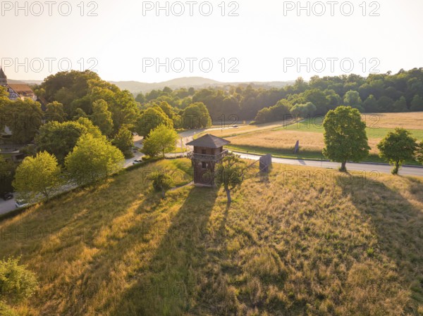 A wooden tower stands in a spacious meadow under the warm evening sun, event and wedding location Lorch Monastery, Lorch, Germany