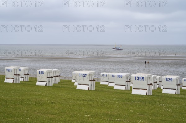 Beach chairs on the green beach, walker on the mudflats, fishing boat, Büsum, North Sea, Schleswig-Holstein, Germany
