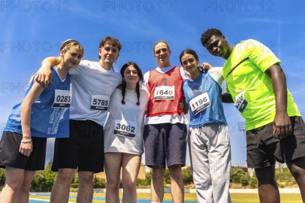 Group of young athletes embracing after a track and field competition, showing sportsmanship and camaraderie