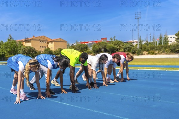 Diverse group of athletes ready to start a race on a blue running track, embodying competition and athleticism