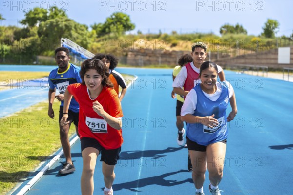 Determined young athletes running on a blue track, striving for victory during a track and field competition