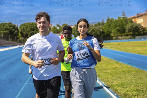 Group of athletes running on a blue track during a sports competition, demonstrating teamwork and determination
