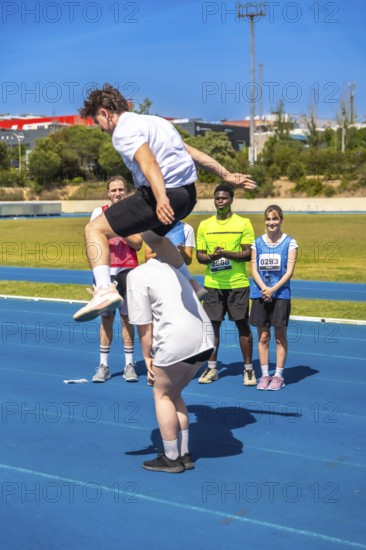 Young athlete jumps over a teammate on a track, showcasing teamwork and athleticism during a track and field competition