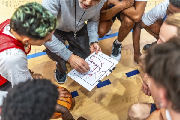 Basketball coach discussing game strategy with his team on a clipboard during a timeout, fostering teamwork and tactical planning